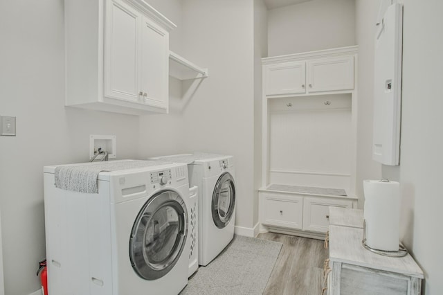 clothes washing area featuring cabinets, washing machine and clothes dryer, and light wood-type flooring