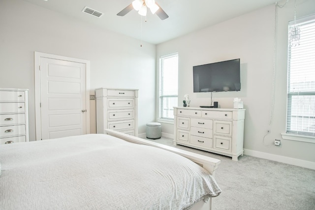 bedroom featuring multiple windows, light colored carpet, and ceiling fan