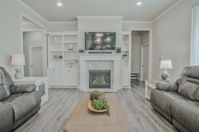 living room with ornamental molding, light wood-type flooring, and a high end fireplace