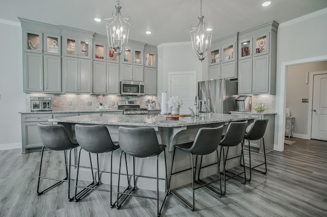 kitchen featuring crown molding, appliances with stainless steel finishes, a large island, and an inviting chandelier