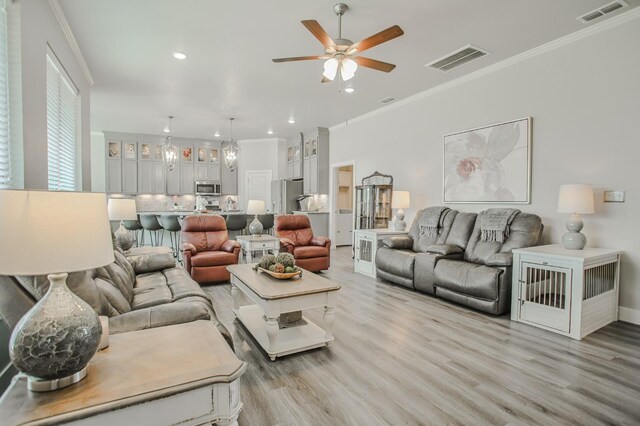 living room with sink, crown molding, light hardwood / wood-style flooring, and ceiling fan