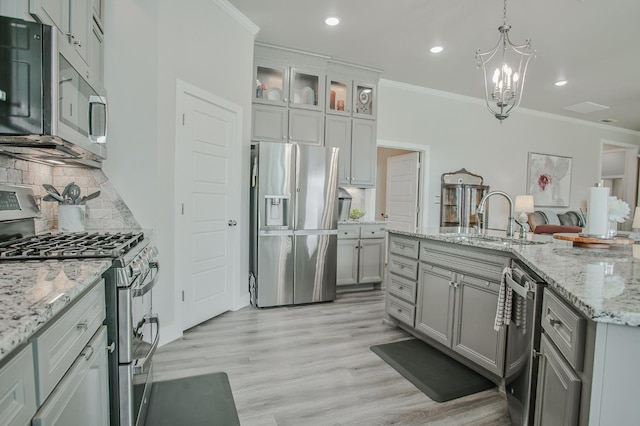 kitchen with stainless steel appliances, gray cabinets, sink, and hanging light fixtures