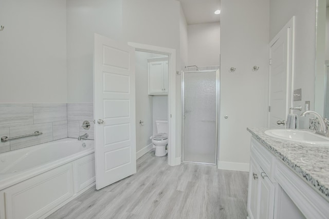 full bathroom with independent shower and bath, vanity, hardwood / wood-style floors, and toilet