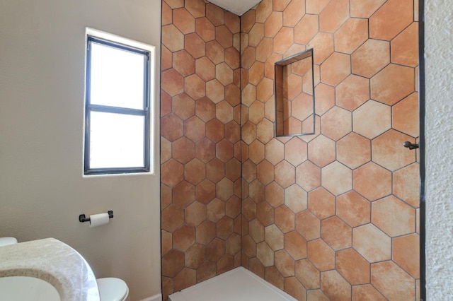 bathroom with a tile shower and toilet