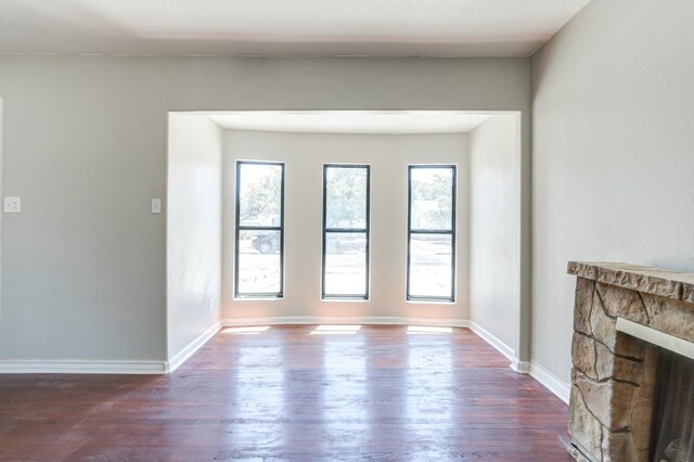 unfurnished living room with dark hardwood / wood-style flooring, a fireplace, and a healthy amount of sunlight