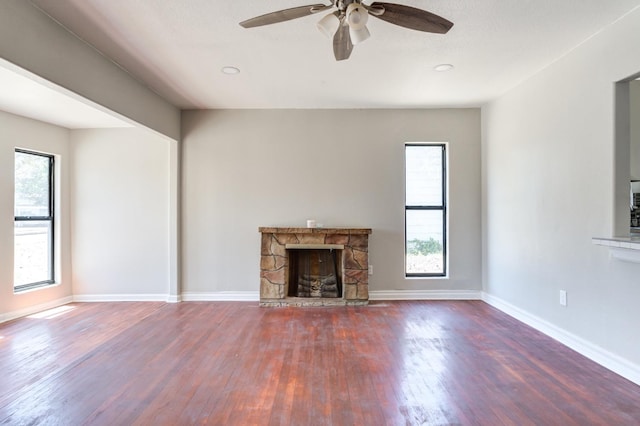 unfurnished living room with a wealth of natural light, a fireplace, dark hardwood / wood-style floors, and ceiling fan