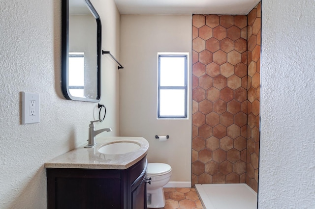 bathroom with vanity, tiled shower, tile patterned floors, and toilet