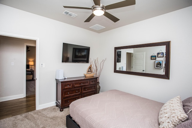 carpeted bedroom featuring baseboards, visible vents, wood finished floors, and a ceiling fan