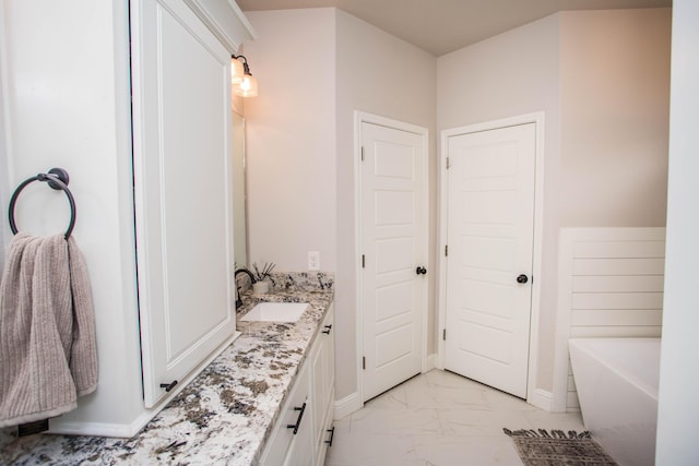 bathroom with vanity, a soaking tub, marble finish floor, and baseboards