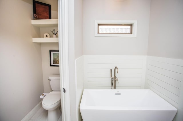 bathroom featuring a freestanding tub, toilet, and a sink