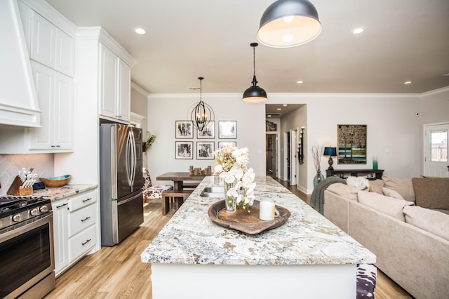 kitchen with white cabinetry, appliances with stainless steel finishes, a center island, an inviting chandelier, and open floor plan