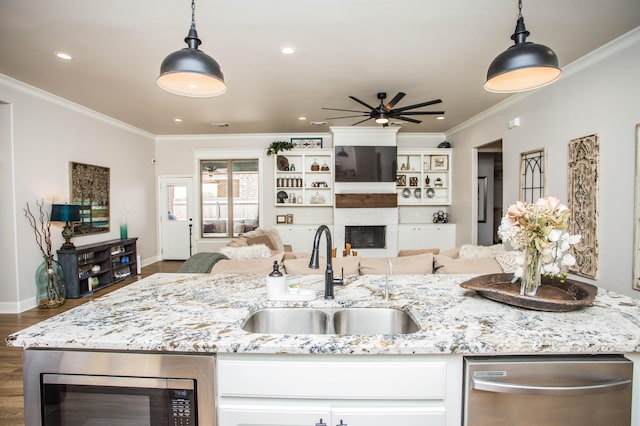 kitchen with appliances with stainless steel finishes, open floor plan, crown molding, and a sink