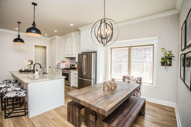 kitchen with white cabinetry, light wood-type flooring, a notable chandelier, and appliances with stainless steel finishes