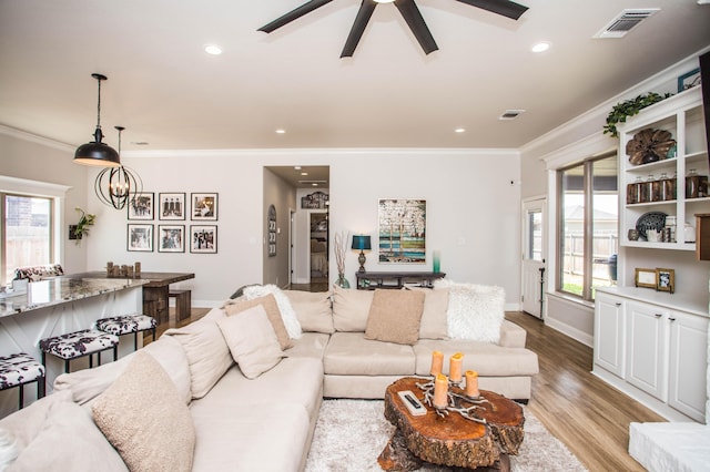 living area featuring visible vents, crown molding, light wood finished floors, and baseboards