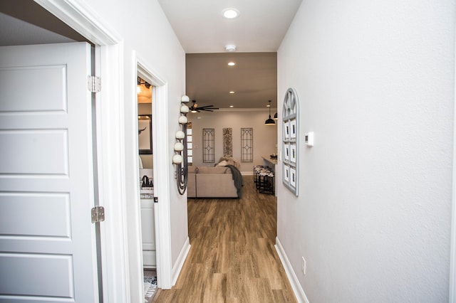 hallway featuring baseboards, recessed lighting, and wood finished floors