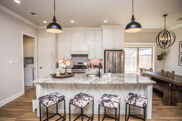 kitchen featuring stainless steel appliances, crown molding, washer / clothes dryer, and custom range hood