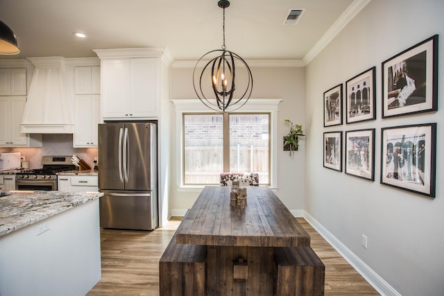 kitchen with light stone countertops, wood finished floors, stainless steel appliances, visible vents, and a notable chandelier