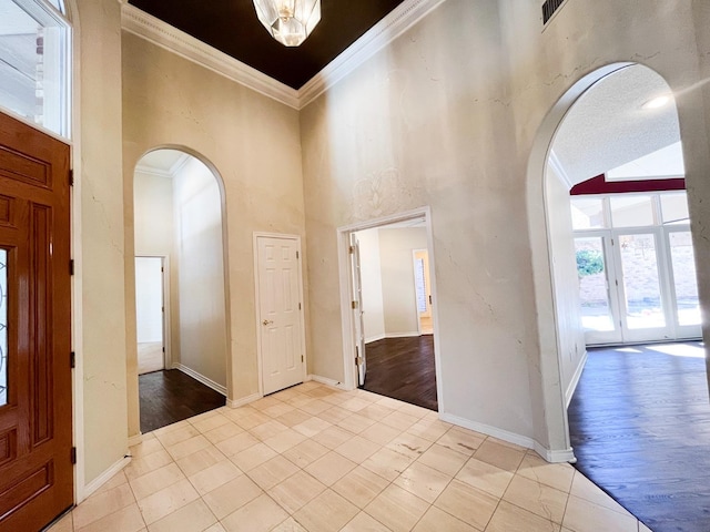 foyer entrance featuring light tile patterned floors, crown molding, and a high ceiling