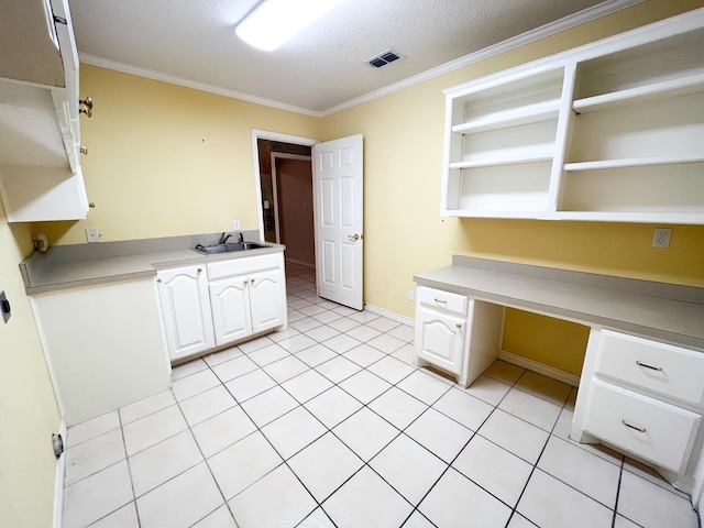 unfurnished office featuring sink, light tile patterned floors, built in desk, ornamental molding, and a textured ceiling