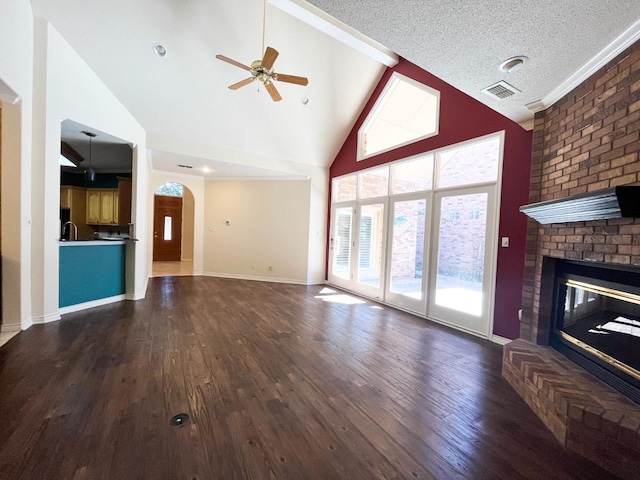 unfurnished living room featuring a brick fireplace, dark hardwood / wood-style floors, a textured ceiling, and ceiling fan