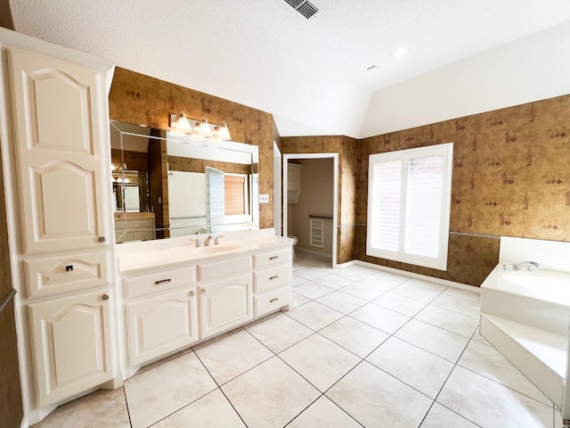 bathroom featuring lofted ceiling, a textured ceiling, vanity, tile patterned flooring, and a washtub