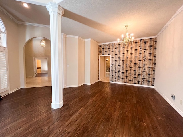 unfurnished room featuring ornate columns, ornamental molding, dark hardwood / wood-style floors, and a notable chandelier