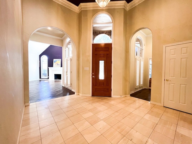 tiled foyer entrance with crown molding and a towering ceiling