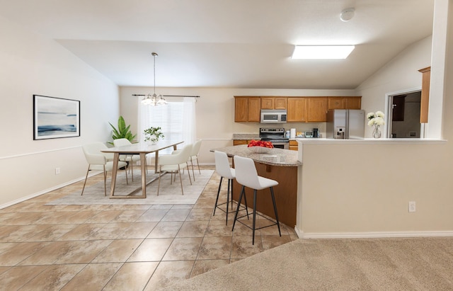 kitchen with appliances with stainless steel finishes, a breakfast bar, lofted ceiling, hanging light fixtures, and an inviting chandelier