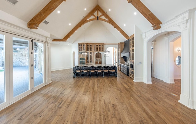 unfurnished dining area featuring beamed ceiling, hardwood / wood-style flooring, high vaulted ceiling, and french doors