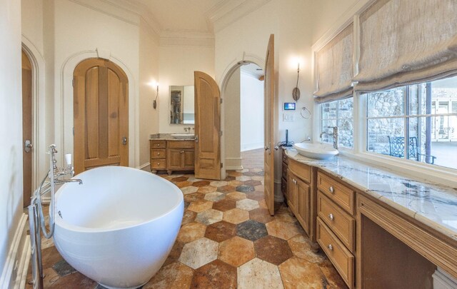 bathroom with crown molding, vanity, and a bath