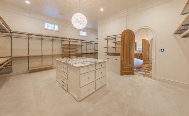 walk in closet with light carpet and a notable chandelier