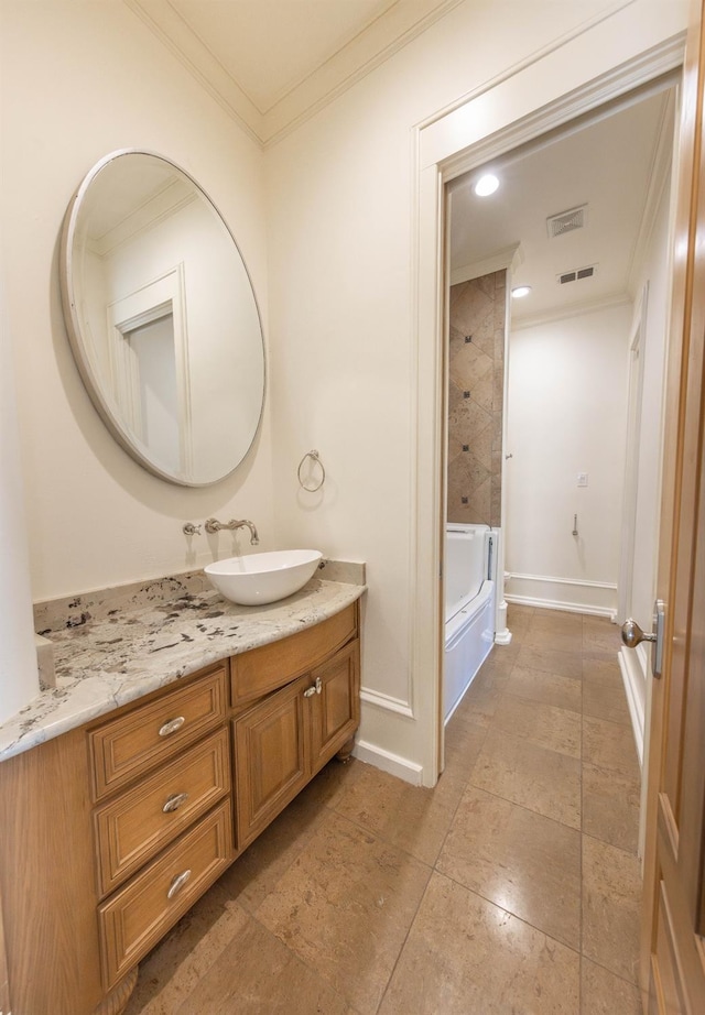 bathroom with vanity, crown molding, and tiled shower / bath