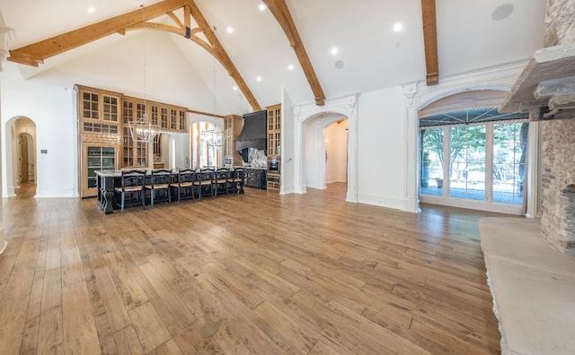 living room featuring beam ceiling, a chandelier, hardwood / wood-style floors, and high vaulted ceiling