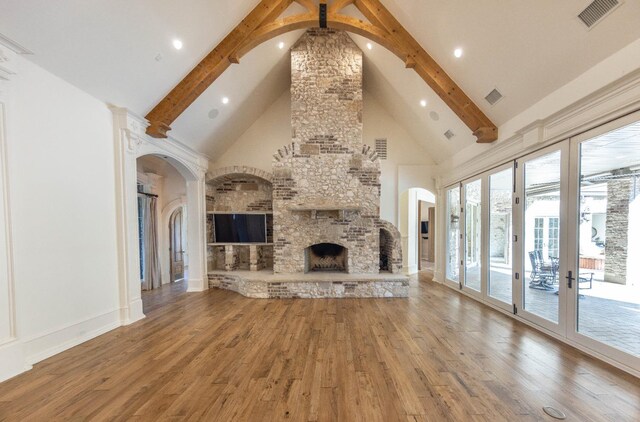 unfurnished living room featuring beamed ceiling, wood-type flooring, a large fireplace, and high vaulted ceiling