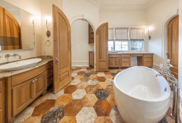 bathroom with ornamental molding, a washtub, and vanity