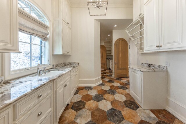 kitchen featuring sink, white cabinets, and light stone counters