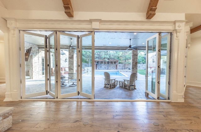 doorway with beamed ceiling, hardwood / wood-style floors, and ceiling fan