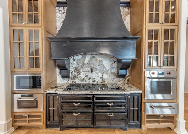 kitchen featuring light stone countertops, appliances with stainless steel finishes, custom range hood, and decorative backsplash