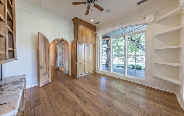 interior space with crown molding, ceiling fan, hardwood / wood-style floors, and built in features