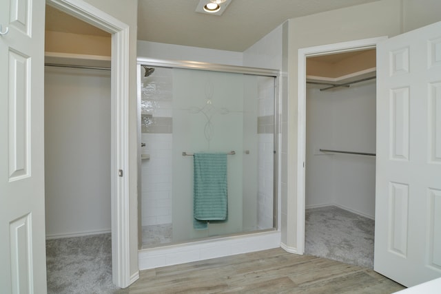 9808 Huron Ave, Lubbock, TX 79424 - full bathroom featuring a spacious closet, a stall shower, and wood finished floors