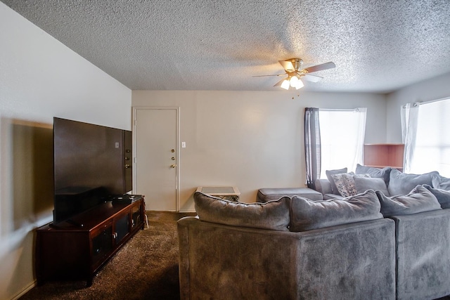 living room featuring ceiling fan, dark carpet, and a textured ceiling