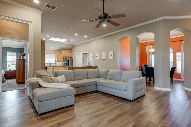 living room featuring ceiling fan, crown molding, dark wood-type flooring, and a textured ceiling