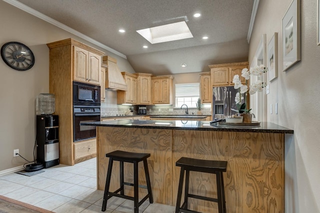 kitchen with premium range hood, vaulted ceiling with skylight, tasteful backsplash, black appliances, and crown molding