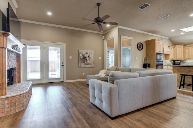 living room featuring a fireplace, ceiling fan, crown molding, dark wood-type flooring, and a textured ceiling