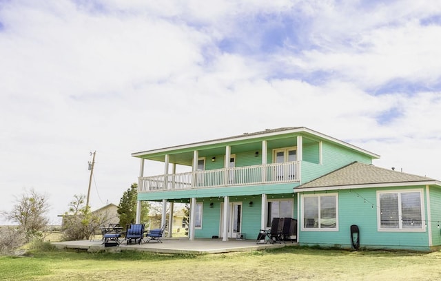 back of house featuring a patio, a balcony, and a lawn