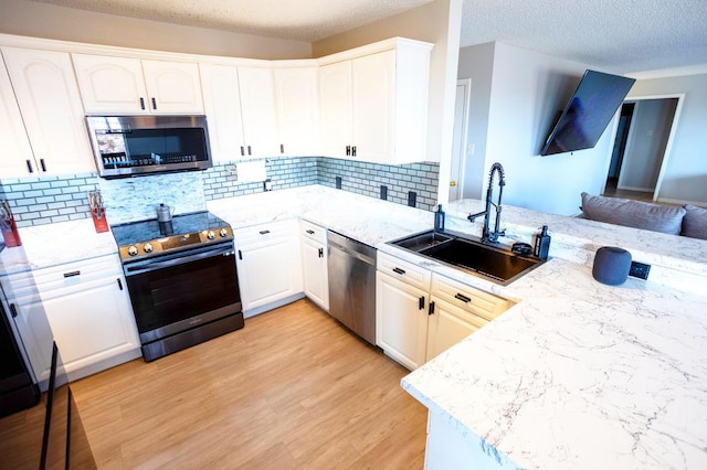 kitchen with white cabinetry, sink, kitchen peninsula, and appliances with stainless steel finishes