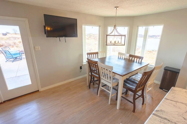 dining area featuring a notable chandelier, a textured ceiling, and light hardwood / wood-style floors