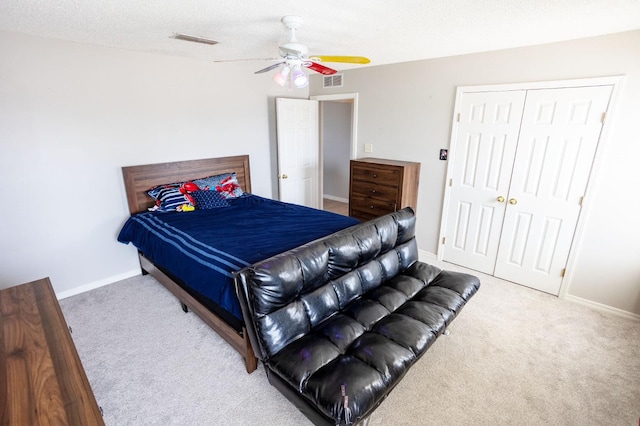 carpeted bedroom featuring ceiling fan, a closet, and a textured ceiling