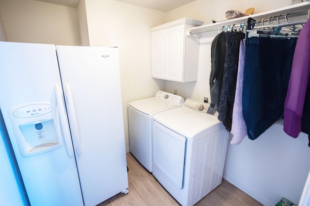 clothes washing area with cabinets, separate washer and dryer, and light wood-type flooring