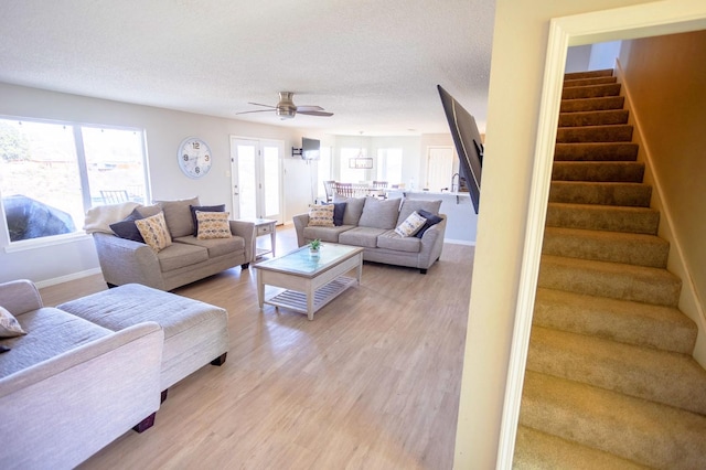 living room with ceiling fan, a textured ceiling, and light wood-type flooring